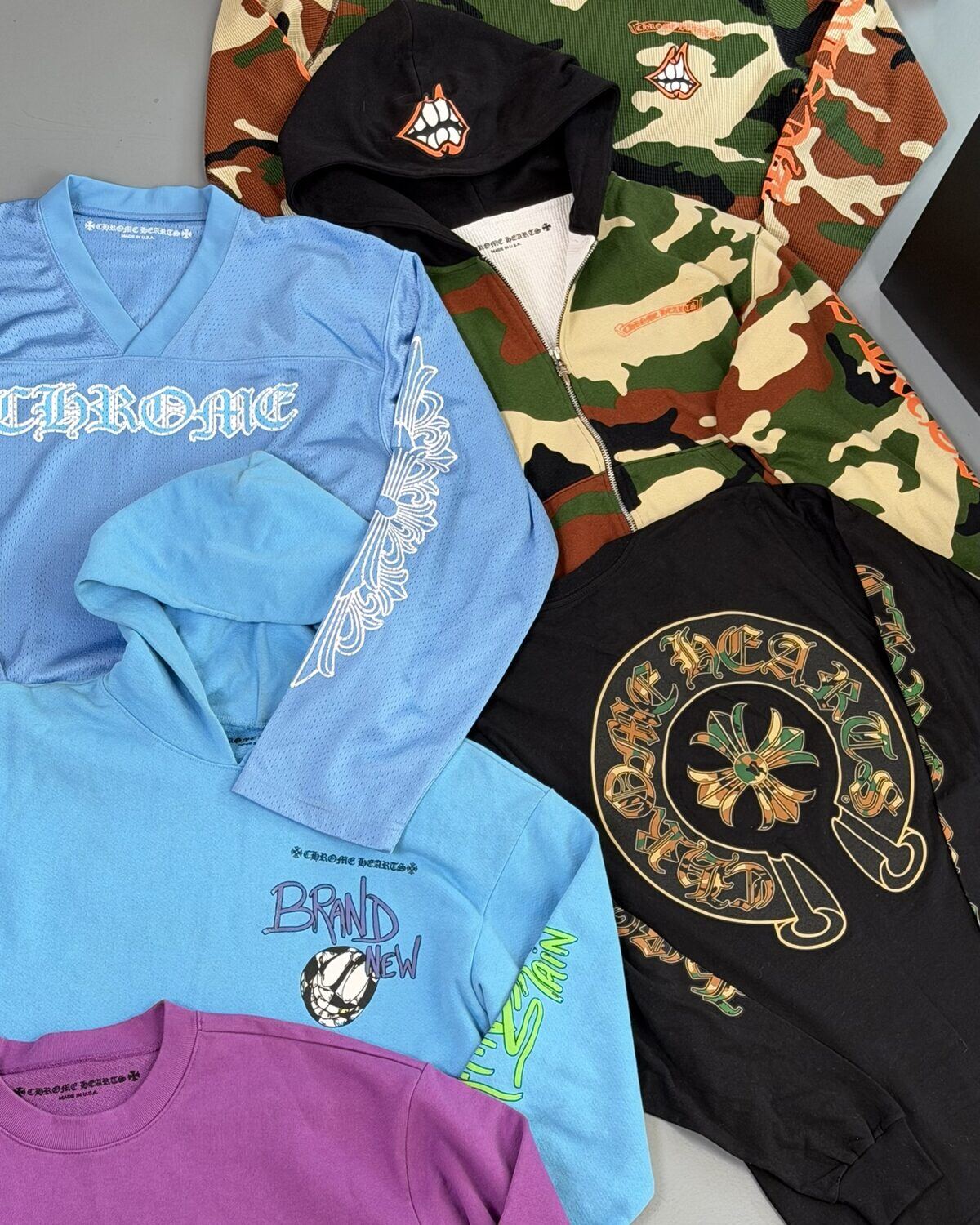 Pre-loved designer t-shirts and hoodies from Chrome Hearts and Bape laid out flat