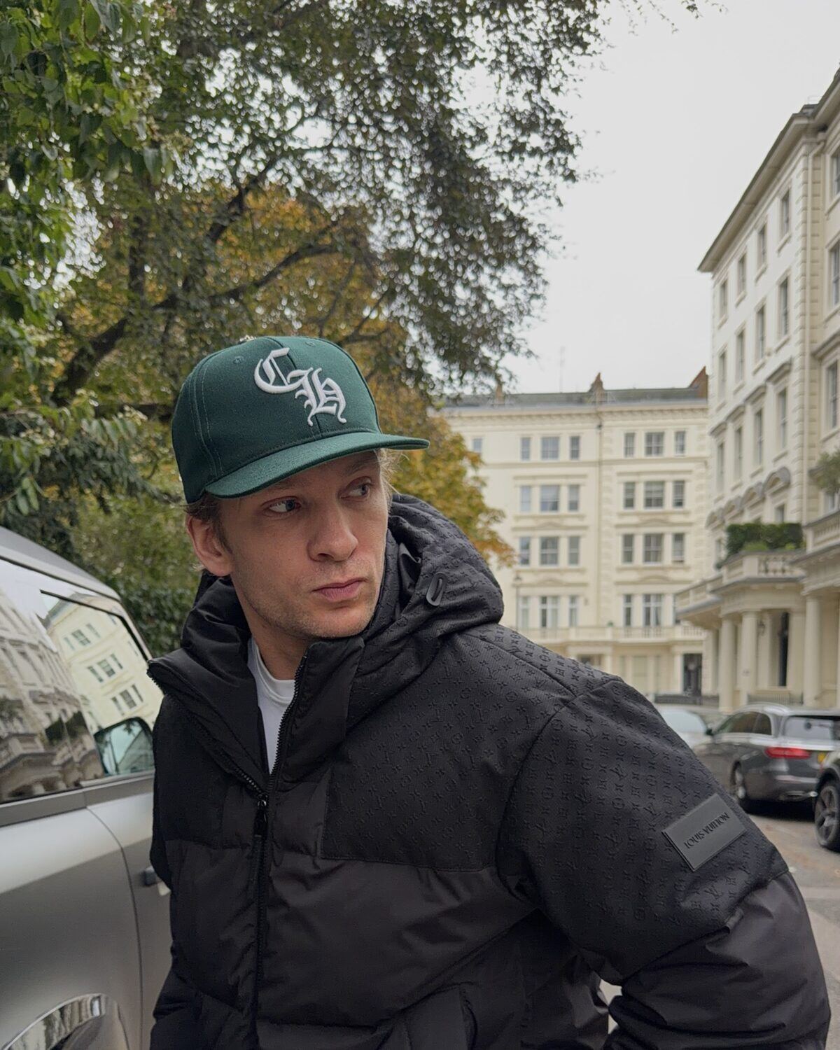 Man wearing a black designer puffer jacket and green cap