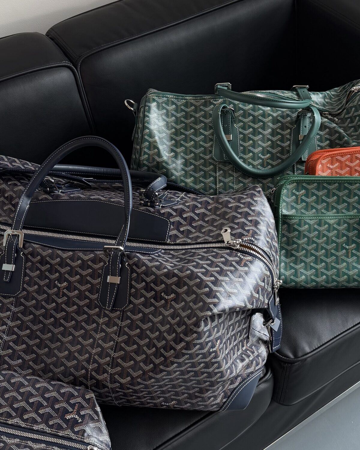 Goyard holdalls and luggage on a black leather sofa